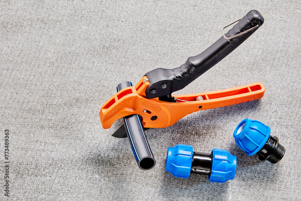 HDPE pipe cutter scissors is cutting water tube when installing household external pipeline for watering garden. HDPE pipe cutter scissors is cutting water tube when installing household external pipeline for watering garden.