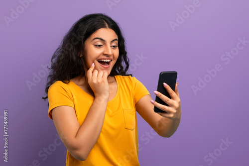 Enthusiastic woman with phone on violet