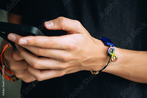 Teenage boy with wristlet with autism infinity rainbow symbol sign on his hand. World autism awareness day, autism rights movement, neurodiversity, autistic acceptance movement