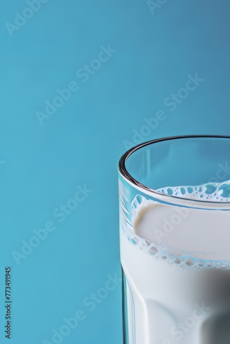 PART OF A GLASS GLASS, FILLED WITH PURE MILK ON A LIGHT BLUE BACKGROUND