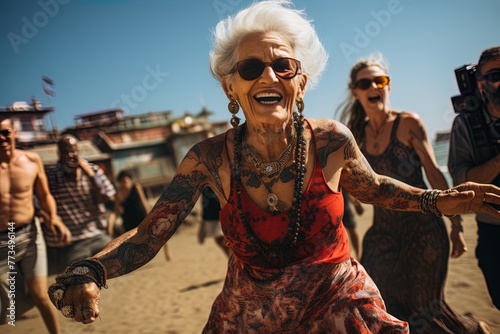 Stylish very old happy lady in is dancing at a beach open air summer party. Grandmother in eyeglasses with white hair. Active aging concept.