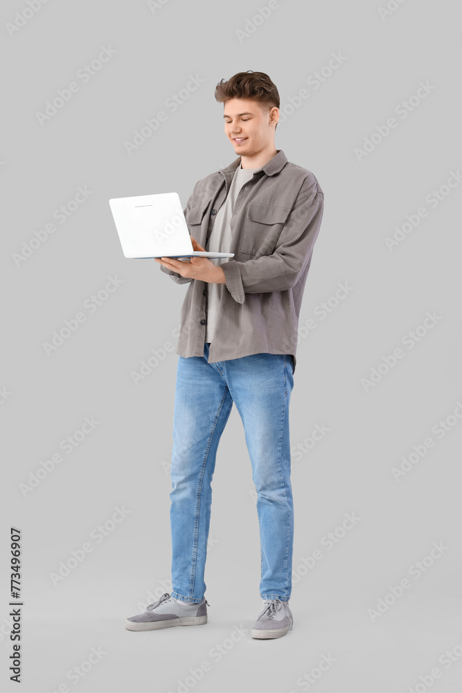Young man using laptop on light background