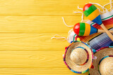 Cinco de Mayo top view scene: sombreros and maracas on display. Colorful serape adorn the yellow wooden desk. Space for text