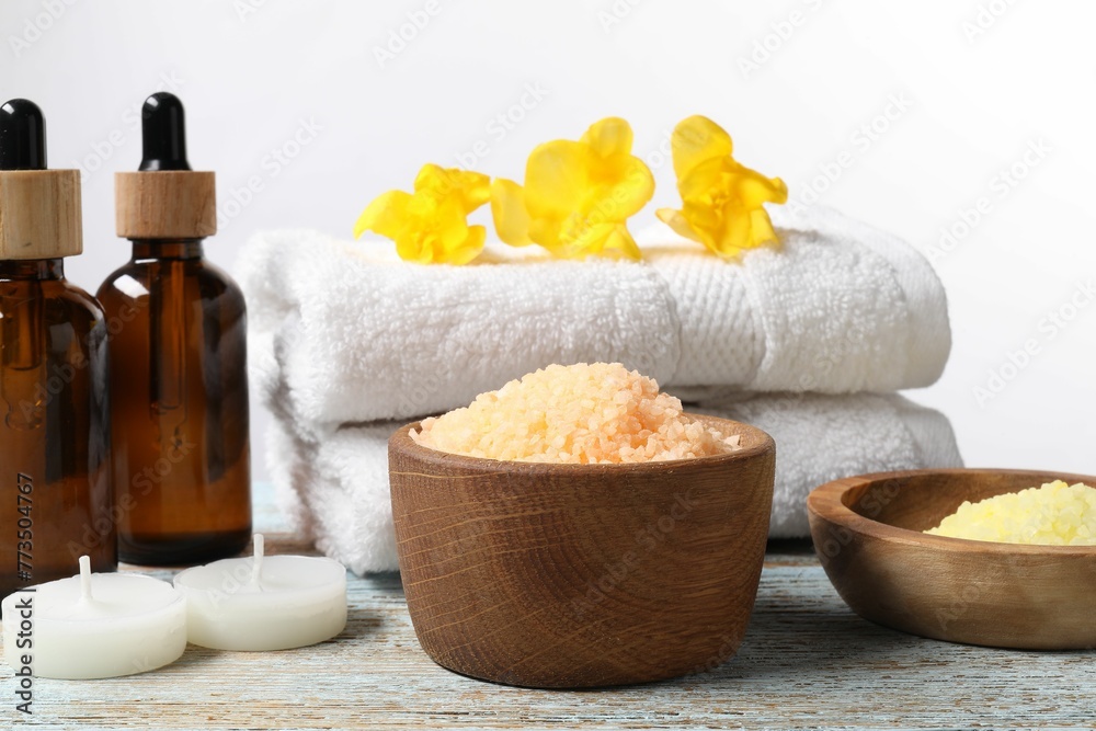 Natural sea salt in bowls and other spa supplies on wooden table against white background Natural sea salt in bowls and other spa supplies on wooden table against white background