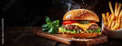 Juicy cheeseburger with steam rising beside golden fries. A delectable beef patty graced with melting cheese on a toasted bun. Panorama with copy space.