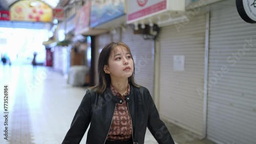 Slow-motion video of an Okinawan woman in her 20s in winter clothes walking in a shopping street near Kokusai Street in Naha City, Okinawa Prefecture 沖縄県那覇市の国際通りの近くの商店街を歩く冬服の20代の沖縄県民女性のスローモーション映像 photo