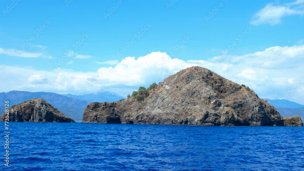 Big rocks in turquoise ocean under sun. A view of sea rocks in the sun rays. A concept of sea trip and cruise leisure in summer. Big rocks in turquoise ocean under sun. A view of sea rocks in the sun rays. A concept of sea trip and cruise leisure in summer.