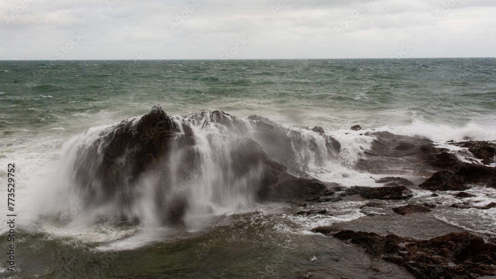 Immense sea rock covered by a large wave. Force of nature.
