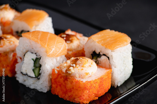 Set of Philadelphia sushi rolls on black plate. Serving Japanese food in restaurant. Popular Asian dish of rice and salmon. Uramaki rolls.