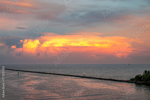 Miami, Florida, USA - July 29, 2023: Mushroom sunset cloud over Fisher Island NE pier with PWC drawing a white line in gray sea water