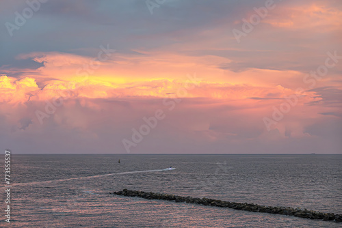 Miami, Florida, USA - July 29, 2023: Mushroom sunset cloud over Fisher Island NE pier with PWC drawing a white line in gray sea water