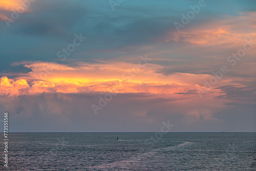 Miami, Florida, USA - July 29, 2023: Sunset clouds over Atlantic Ocean with PWC drawing a white line in gray sea water
