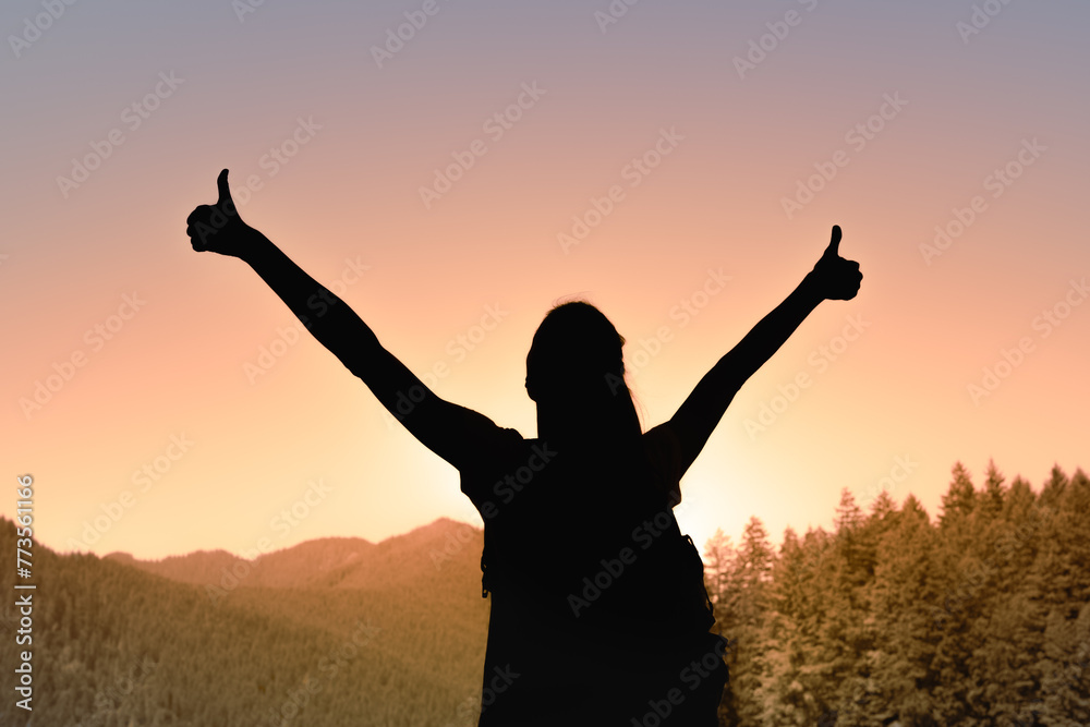 Young woman arms outstretched on a mountain at sunrise enjoying freedom and life, people travel wellbeing concept
