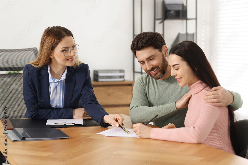 Happy couple signing document in lawyer's office Happy couple signing document in lawyer's office