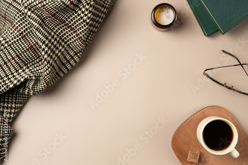 Book, glasses, candle, plaid, with cup coffee on beige background. Leisure concept, reading a book. Flat lay, top view