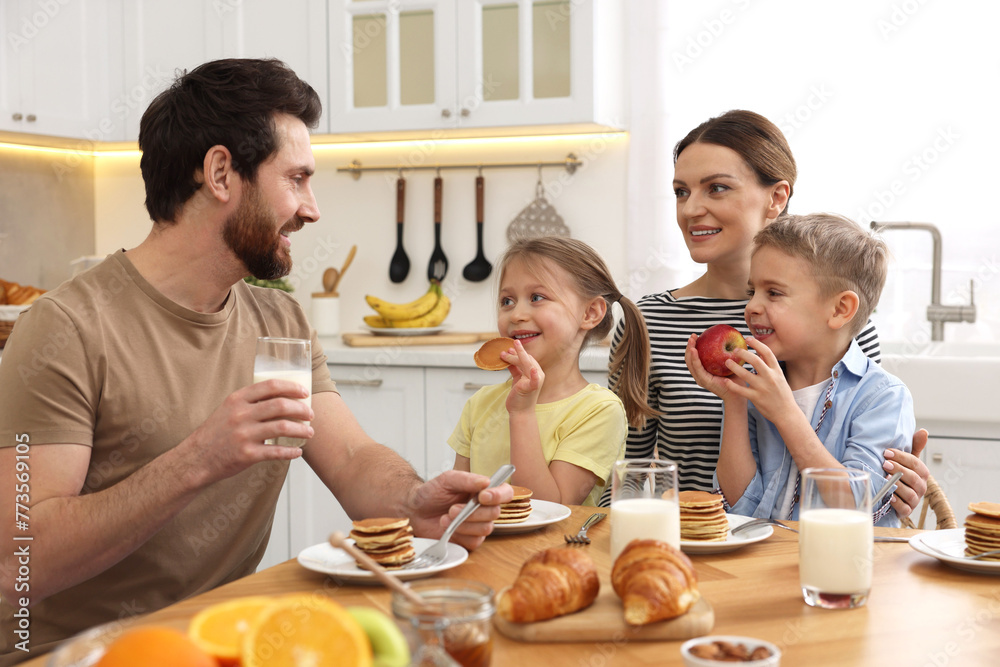 Happy family having fun during breakfast at table in kitchen Happy family having fun during breakfast at table in kitchen