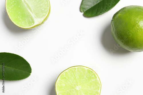 Fresh ripe limes and leaves on white background, flat lay