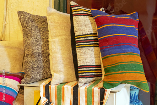 Decorative colorful soft textile pillows on a shelf interior © Tatty