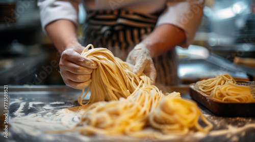 A detailed close-up captures the hands of a chef dusted with flour as they skillfully shape fresh, golden pasta dough into thick noodles.