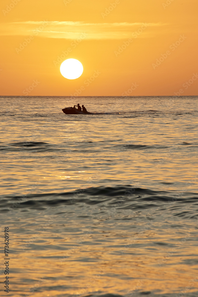People on a jet ski against the background of the setting sun
