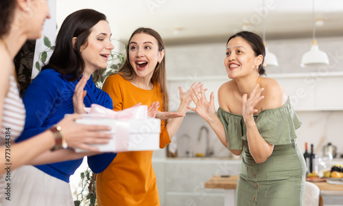 In homely atmosphere, girl meets female three guests, accepts congratulations, gift. Class mate female friends are happy to meet and kiss each other on cheek. Hostess of house invite guests into home