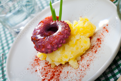 Seafood dish - boiled octopus with potato served with paprika on plate photo