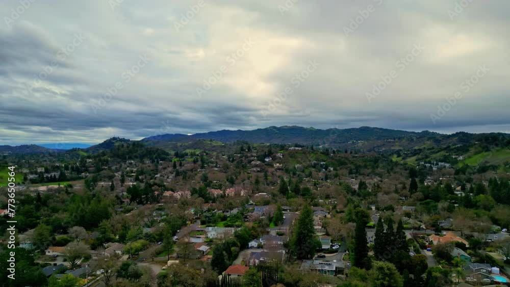 Aerial view of a residential area nestled in hilly terrain with heavy clouds on the sky and horizon Aerial view of a residential area nestled in hilly terrain with heavy clouds on the sky and horizon