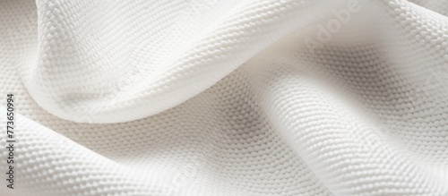 A close-up view of a soft white towel neatly placed on a pristine white background, emphasizing simplicity and cleanliness
