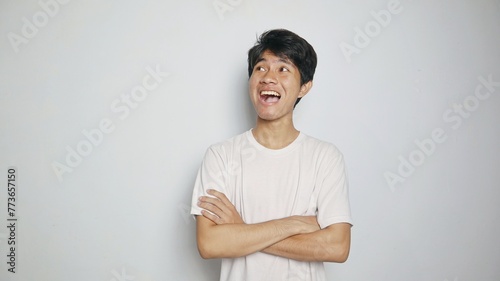 Handsome Asian young man smiling posing crossing both arms on his chest and looking up