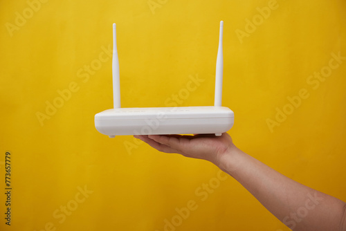 Photo of female hand holding an internet router on yellow background photo
