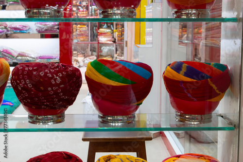 Display of modern turbans, headwear based on cloth winding with many variations, customary headwear for many. Bright, colorful men's costume displayed under glass show case. Jodhpur, Rajasthan, India. photo