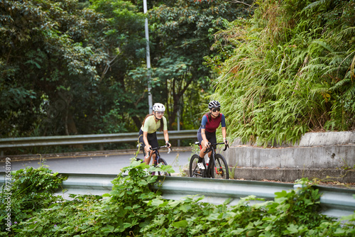 two young asian female cyclists riding road bikes in the countryside