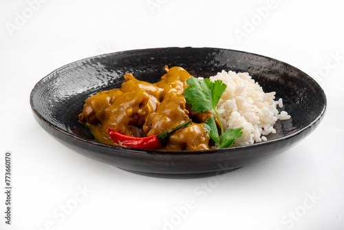 Juicy pieces of chicken with curry sauce and white rice on a plate on a white background