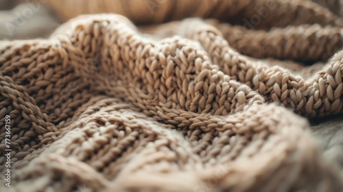 Close-up of a thick, knitted beige blanket with a textured pattern, depicting comfort and warmth with a cozy feel.