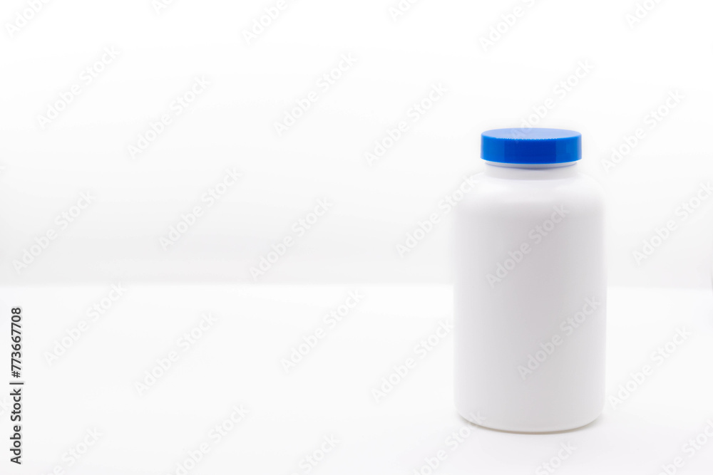 White medicine or vitamin bottle with blue lid isolated on white background with copy space