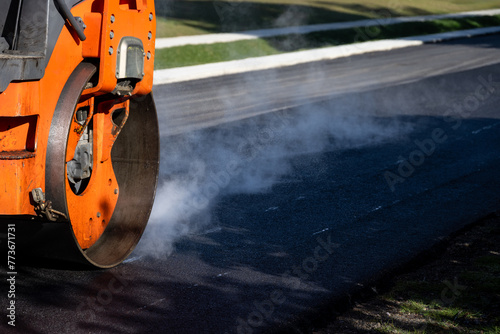 Closeup of steamroller compacting freshly load asphalt, residential road repaving construction project
 photo