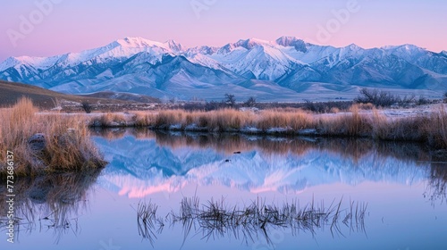Snow-capped mountains reflect in tranquil waters at twilight with hues of purple and blue dominating the serene landscape.