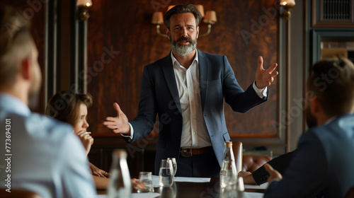  In a conference room, a confident team leader stands at the head of the table, delivering a persuasive pitch to his colleagues and potential investors photo