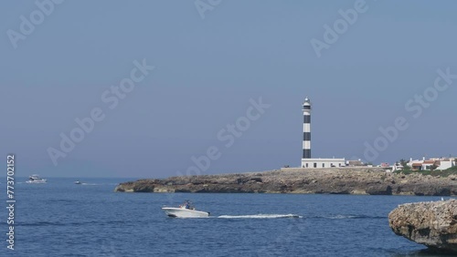 Speed boat near Cap d'Artrutx Lighthouse at Son Xoriguer beach of Cala en Bosch resort in Menorca Island Spain photo