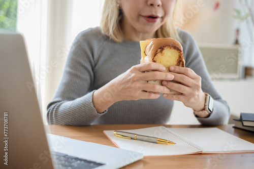 Student sitting in cafe  eating fast food and watching laptop
