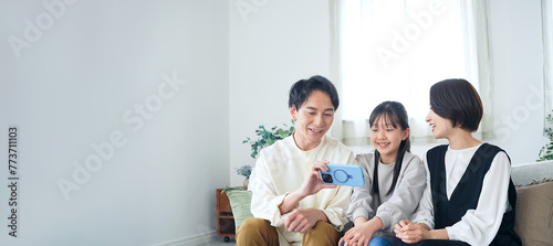 A family of an Asian girl and her parents looking at a smartphone screen.