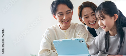 A family of an Asian girl and her parents looking at a tablet PC screen. photo