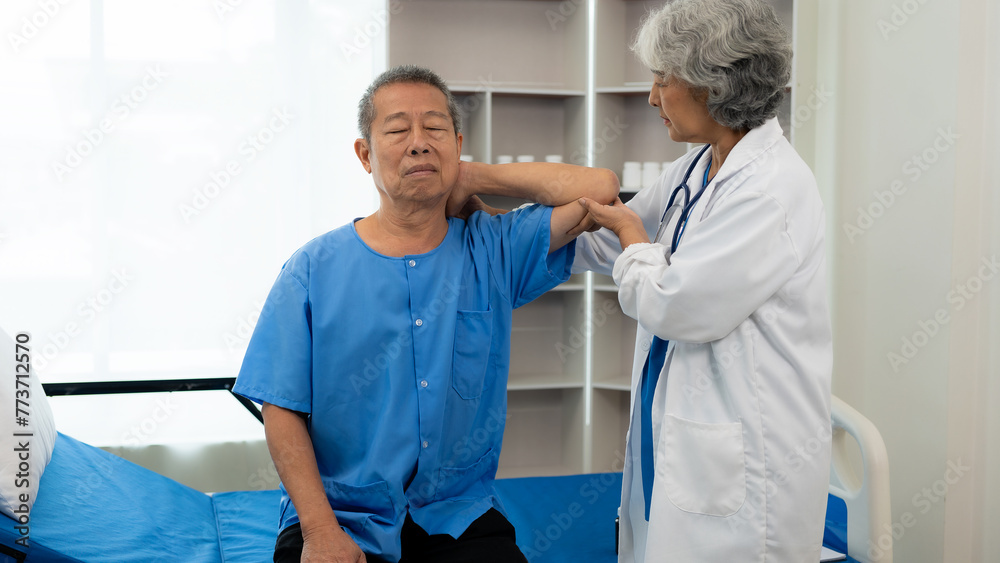 Fototapeta premium An old Asian man is doing physical therapy with the support of an elderly female nurse in the living room by a patient with a nursing attendant.