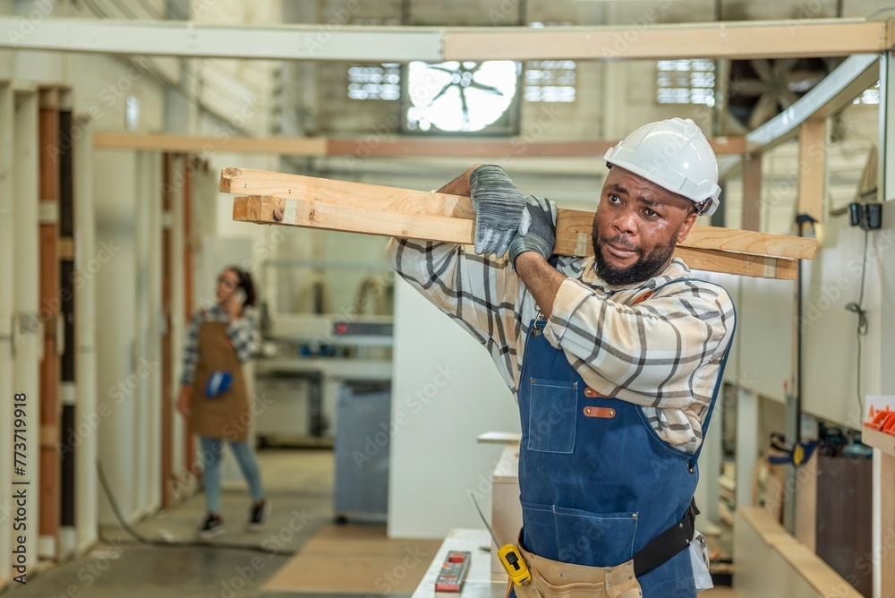 Carpenter man Portrait of Young black skin working in workshop. Happy professional Carpenter holds wooden planks for build furniture in carpentry workshop. carpenter worker make furniture in DIY shop