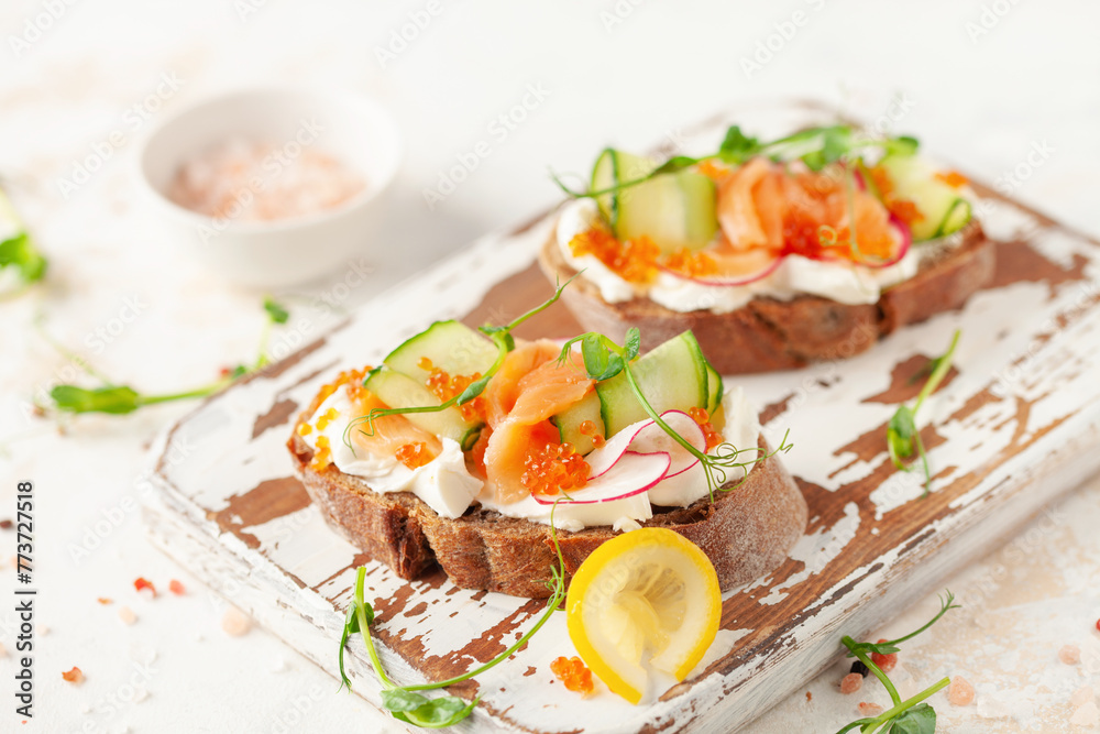 Sandwich with vegetables and salmon on a wooden board. Ciabatta sandwich. Sandwich with vegetables and salmon on a wooden board. Ciabatta sandwich.