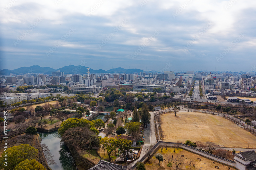 Fototapeta premium View from rooftop of famous Unesco Word Heritage site Himeji-jo castle over park and Japanese City of Himeji on a cloudy gray winter day. Photo taken February 1st, 2024, Himeji, Japan.