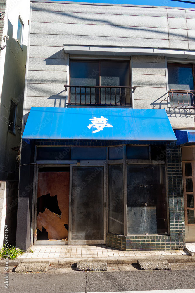 Φωτογραφία Wrecked former shop with white Japanese character dream on blue sunshade at Japanese City of Tokyo on a sunny winter day