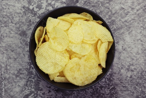 Potato Chips Snack in black bowl, close up photo top view