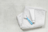 Towel with children's toothbrush and toothpaste on white grunge background