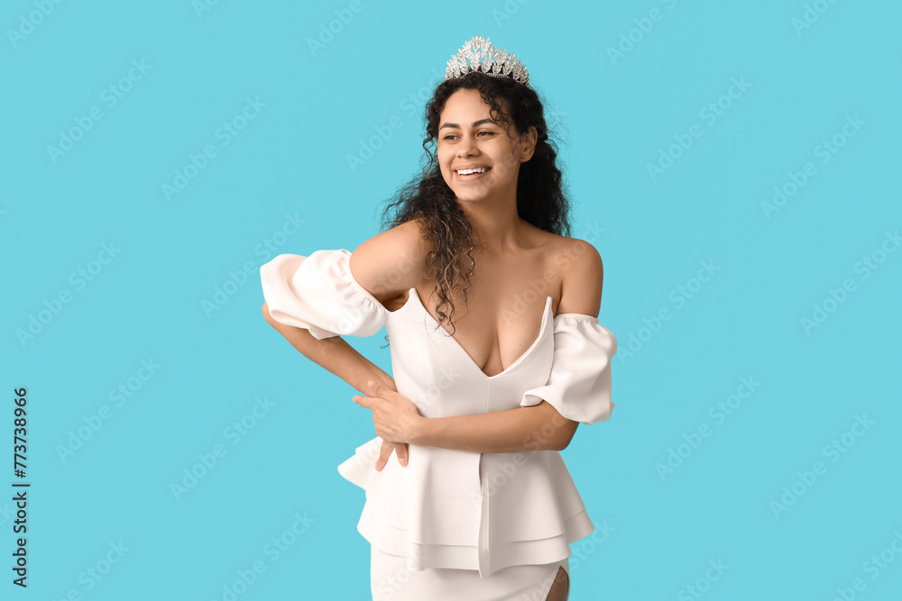 Beautiful young African-American woman in stylish white prom dress and tiara on blue background Beautiful young African-American woman in stylish white prom dress and tiara on blue background